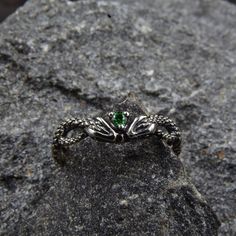 This unique silver engagement ring features a stunning design with twin snakes wrapping around each other, facing each other, and holding a sparkling emerald between their heads. The intricate detailing of the snakes' scales and the vivid green of the emerald make this ring a truly eye-catching piece of jewelry.  Characteristics: Metal - Recycled solid sterling silver  Stone - Cubic Zirconia Finish - Oxidized. View all silver gothic rings: https://www.etsy.com/shop/TinyShinyJewel?ref=seller-platform-mcnav&section_id=42765371 Care instructions: To care for the ring, avoid contact with water and chemicals such as perfumes and lotions. When the ring is not in use, store it in a dry, cool place to prevent tarnishing. Additional information:  ✦ All rings are made to order. An average turnaround Adjustable Silver Magical Style Rings, Mystical Gemstone Rings For Collectors, Silver Symbolic Gemstone Rings, Adjustable Mystical Sterling Silver Rings, Symbolic Silver Gemstone Rings, Mystical Collectible Gemstone Rings, Symbolic Silver Rings With Gemstone, Spiritual Ring Jewelry With Accent Stones, Spiritual Jewelry Ring With Accent Stones