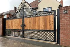 an iron gate with wooden paneling in front of a brick house