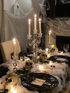 a table set with candles and skulls on the table cloths for a halloween party