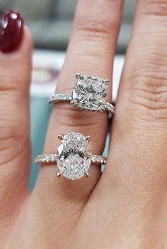 a woman's hand with two engagement rings on top of her finger and the other ring