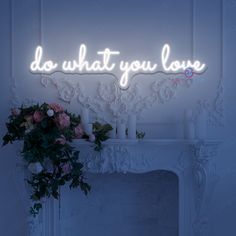 a lit up sign that says do what you love on the wall next to a fireplace