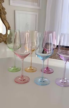 five wine glasses are lined up on a counter in front of a gold framed mirror