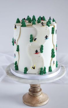 a white cake with green trees and skiers on it