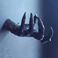 a hand that is hanging on the wall with black paint and nails sticking out of it