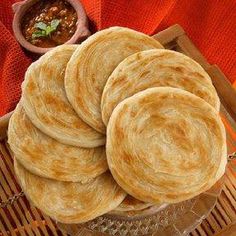 several flat breads are stacked on a plate next to a bowl of chili sauce