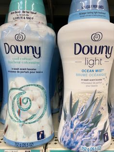 two bottles of downy light are on display for sale in a grocery store, one is blue and the other is white