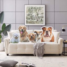 a group of dogs sitting on top of a white couch next to a painting and pillows