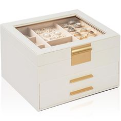 a white box with gold handles and drawers filled with rings, bracelets and earrings