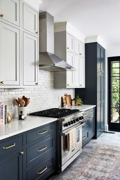 a kitchen with white and blue cabinets, an oven, stove top and rug on the floor