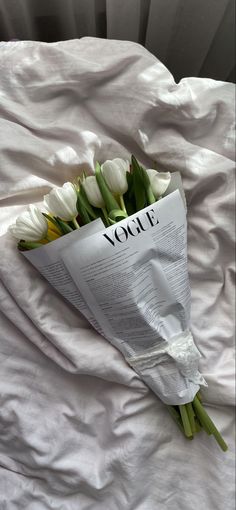 a bouquet of white tulips laying on top of a bed with the word you