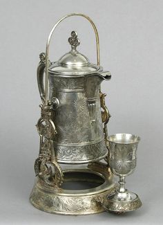 an antique silver coffee pot and two cups