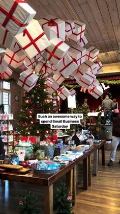 a christmas tree with presents hanging from it's ceiling and people looking at them