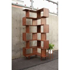 a tall wooden shelf sitting next to a cement wall