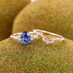 a blue and white diamond ring sitting on top of a moss covered surface