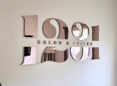 the salon and suites logo is displayed on a wall with mirror cutouts around it