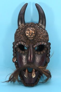 a mask with long hair and horns on it's face, against a blue background