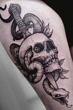 a skull and snake tattoo on the thigh