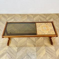 a coffee table with a glass top and wooden legs on a chevron wood floor