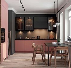 a kitchen with wooden floors and pink cabinets, along with a dining table in the center