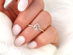 a woman's hand holding a ring with a diamond on the middle of it