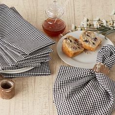 two pieces of bread are on a plate next to napkins and a teapot