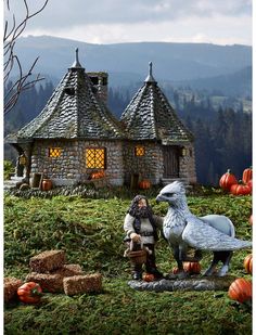 a statue of a man and a bird in front of a house with pumpkins