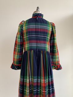 "This is a festive handmade garment from the 1960's. The dress is in a lightweight organic material in a blue plaid pattern. The neckline, bodice, and wrist are trimmed with a red cord and ruffle. The dress looks to be handmade and shows no visible flaws. The dress is semi-sheer, and a slip would be recommended. The dress is in excellent condition. Measurements: Bust: 37\" | Waist: 35\" | Hips: Free | Shoulders: 14\" | Sleeves\" 23\" | Length: 48\" Unless otherwise stated all vintage items are u Fitted Blue Plaid Cotton Dress, Retro Plaid Dresses With Ruffles, Retro Plaid Dress With Ruffles, Vintage Lined Plaid Dress, Vintage Plaid Cotton Dress, Blue Plaid Pattern, Blue Plaid Dress, Handmade Dress, Vintage Gowns