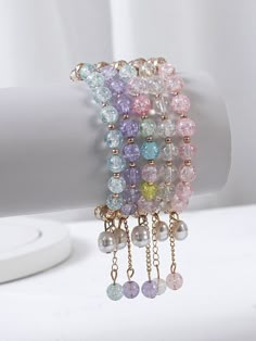 multicolored bracelets with pearls and chains on a white table next to a candle