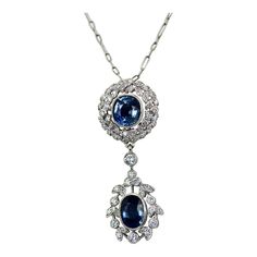 This is part of Chairish’s Fine Jewelry assortment.  Vintage Sapphire Diamond 18K Drop Necklace  This necklace is made in 18K White Gold and features 2 beautiful Blue Sapphires. The style is modern yet bears a vintage drop necklace style. The necklace is 18" long and has (1) oval Sapphire of 1.25 carats the other Sapphire drop is round and weighs .75 carats. This totals 2 carats of Sapphires. Diamond surround the Sapphires in wreath style and the bottom Sapphire has a Diamond surround. The Diamo Formal Oval Necklace With 17 Jewels, Luxury Oval Jeweled Necklaces, Luxury Jeweled Oval Necklaces, Formal Oval Necklaces With 17 Jewels, Exquisite Oval Jewel Necklaces, Oval Diamond Necklace With Jewels, Elegant Oval Pendant Gemstone Drop Necklace, Elegant Oval Drop Necklace For Formal Occasions, Heirloom Blue Necklaces For Weddings