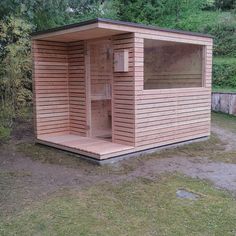 a wooden outhouse sitting on top of a lush green field next to a forest