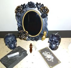 there is a mirror, skull candles and other items on the table