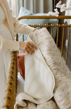 a baby in a crib is being held by a woman who is holding a blanket