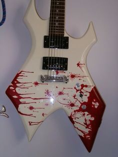 a white electric guitar with red paint splattered on it