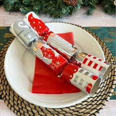 two christmas utensils sitting on top of a white plate with red napkins