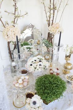 a table topped with lots of vases filled with flowers and plants next to each other