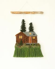 a wall hanging with a house and trees on it