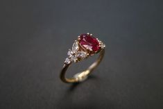 a diamond and ruby ring on a black surface