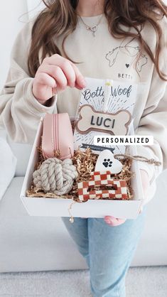 a woman is holding a box full of personalized items for her dog's birthday