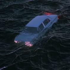 a car that is sitting in the water with it's hood up and lights on