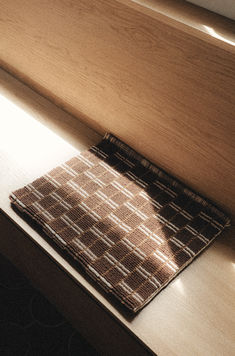 a cloth sitting on top of a wooden counter next to a window sill with sunlight coming through it