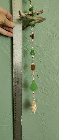 a person measuring the length of a piece of glass beaded necklace on a ruler