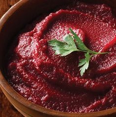 a wooden bowl filled with red sauce and garnished with parsley