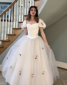 a woman in a white dress standing next to stairs