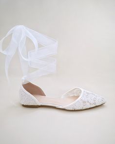 a pair of white wedding shoes with a ribbon