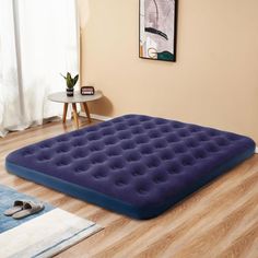 an inflatable mattress is on the floor next to a rug and table with shoes