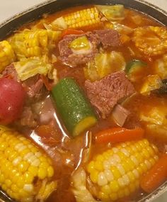 corn on the cob soup with meat and vegetables in a metal bowl, ready to be eaten