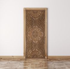 an ornate wooden door in the corner of a room with hard wood flooring and white walls