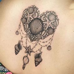 a woman's back with a tattoo on it that has shells and starfishs hanging from it