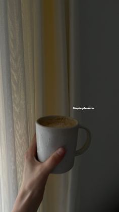 a person holding a cup of coffee in their hand