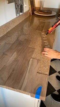 a person is using a knife to cut out the wood for a counter top that has been installed